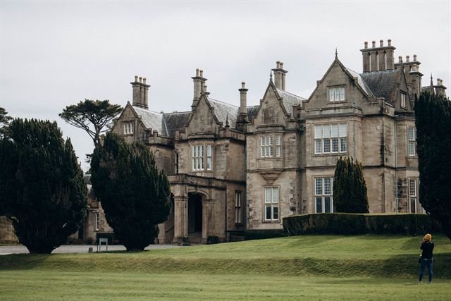 Muckross House, a Victorian stone mansion with tall chimneys and lawns in Killarney