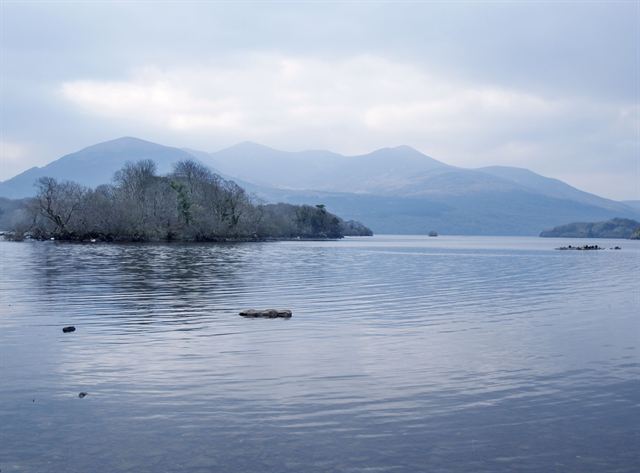 Lough Leane in Killarney with a wooded islet and misty mountains beyond