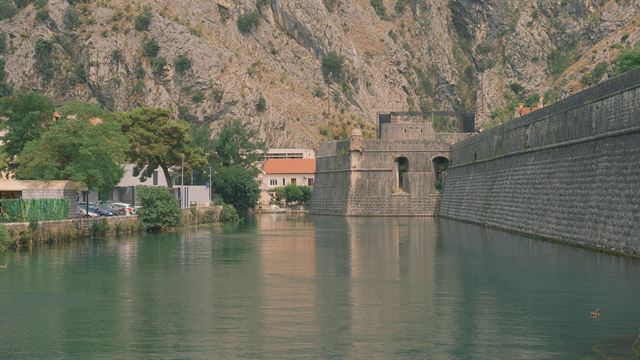 Kotor's Venetian city walls and Bembo bastion reflected in the Škurda River below limestone cliffs