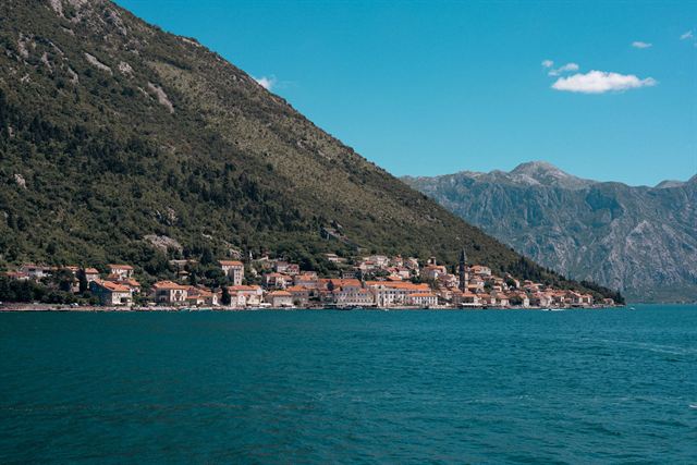 Seaside village strung along the turquoise Bay of Kotor beneath steep green mountains in Montenegro