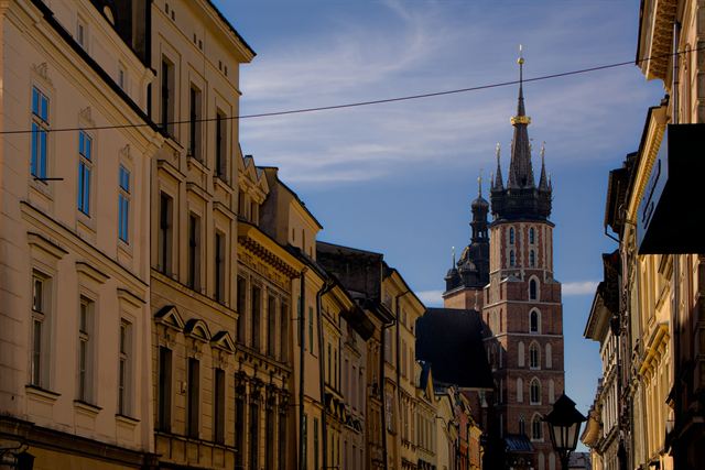 Historic Krakow street of tall facades leading to the Gothic spire of St. Mary's Basilica