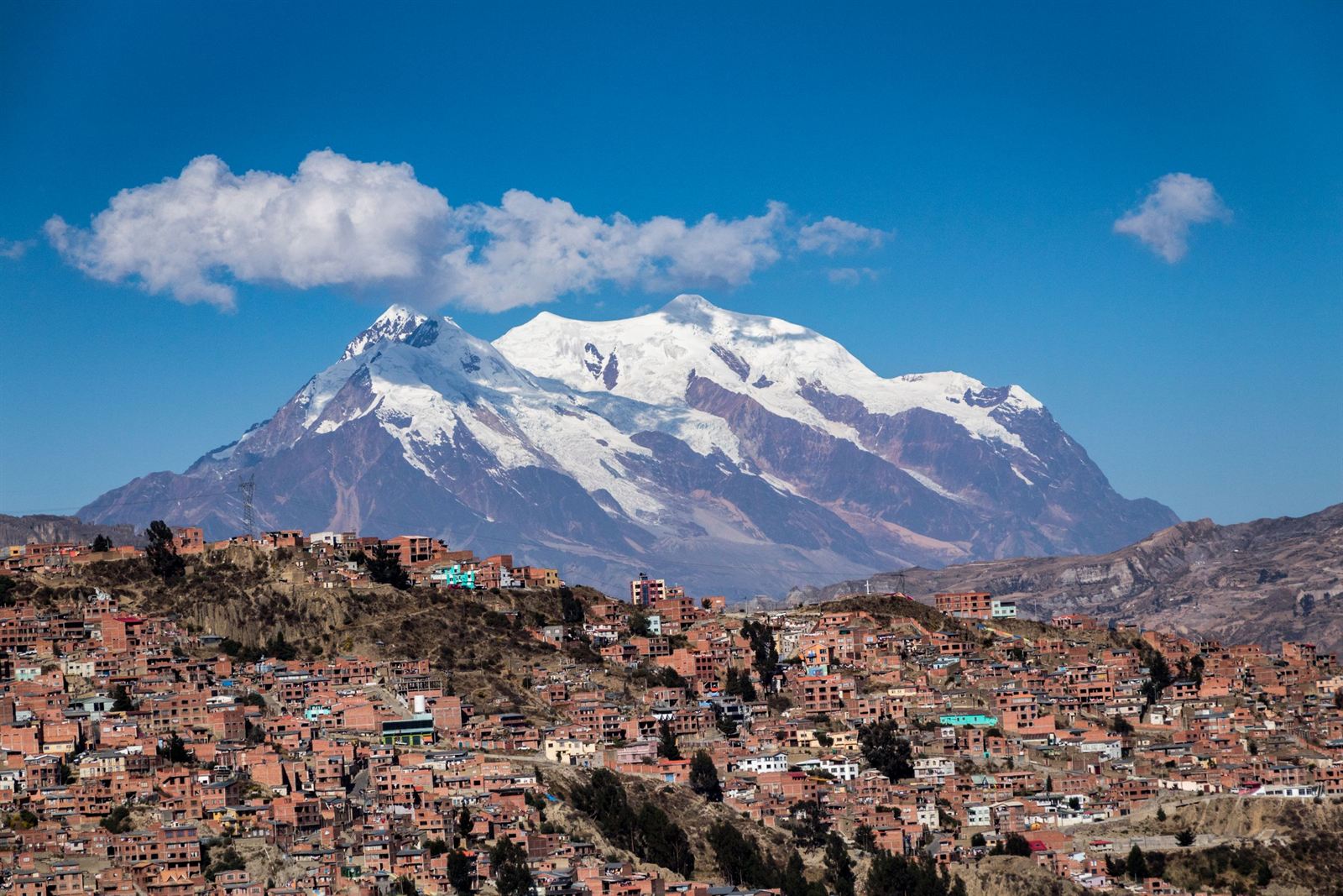 Snow-covered Mount Illimani towering above the red-brick hillside neighborhoods of La Paz, Bolivia