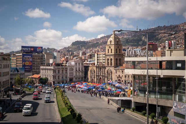 Busy La Paz street with the colonial San Francisco church, market stalls and hillside city