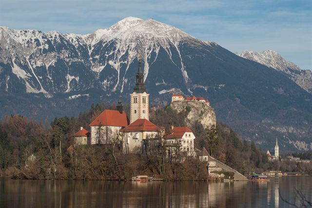 Bled Island's Church of the Assumption and bell tower with snow-capped Julian Alps peaks behind