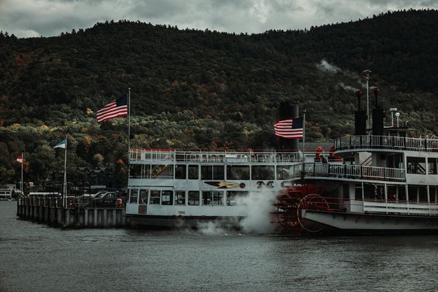 Lake George steamboats with American flags docked at Lake George village beneath autumn-colored mountains