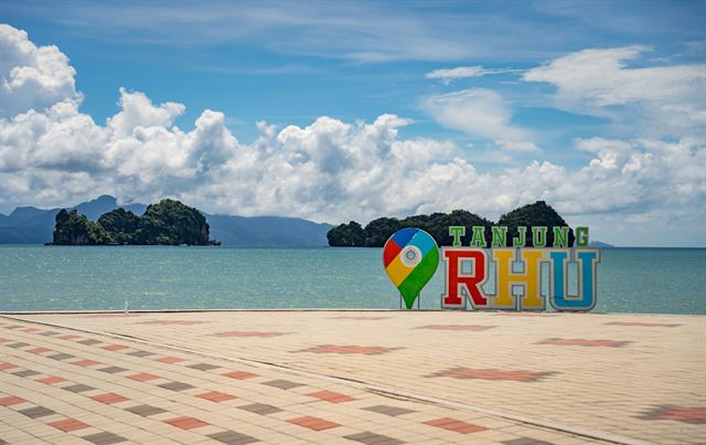 Tanjung Rhu beach promenade in Langkawi with its colorful name sign and limestone islets offshore