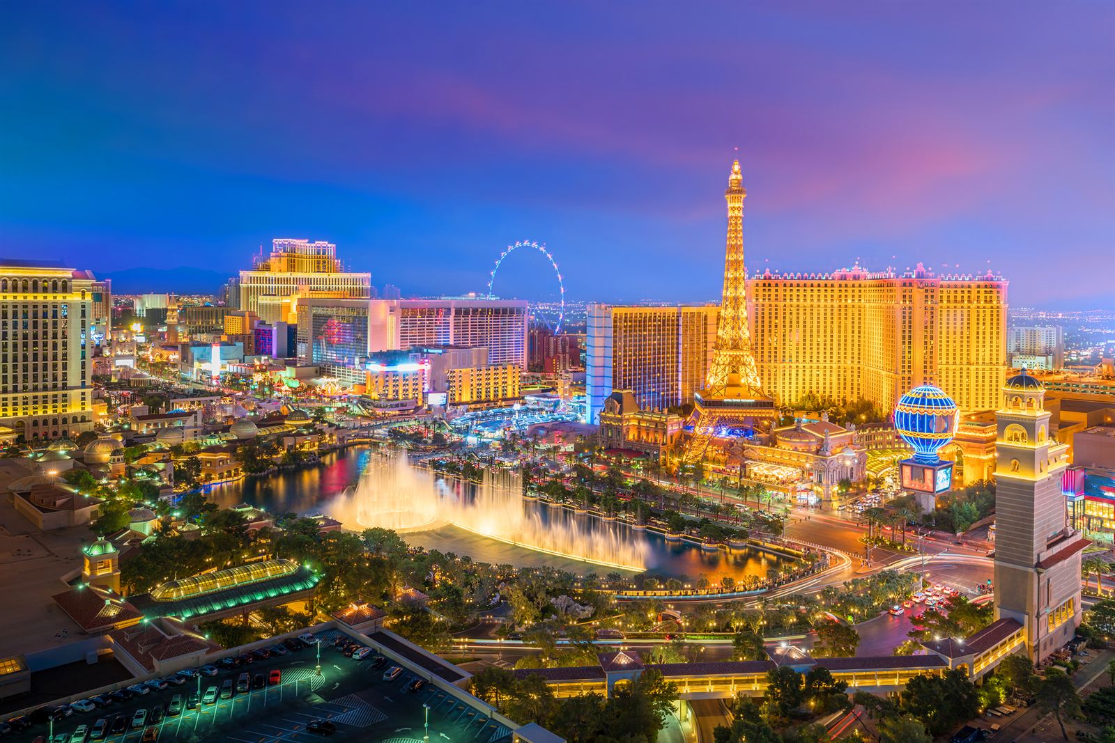 Las Vegas Strip at dusk with the Bellagio fountains, the Paris Eiffel Tower replica and the High Roller wheel