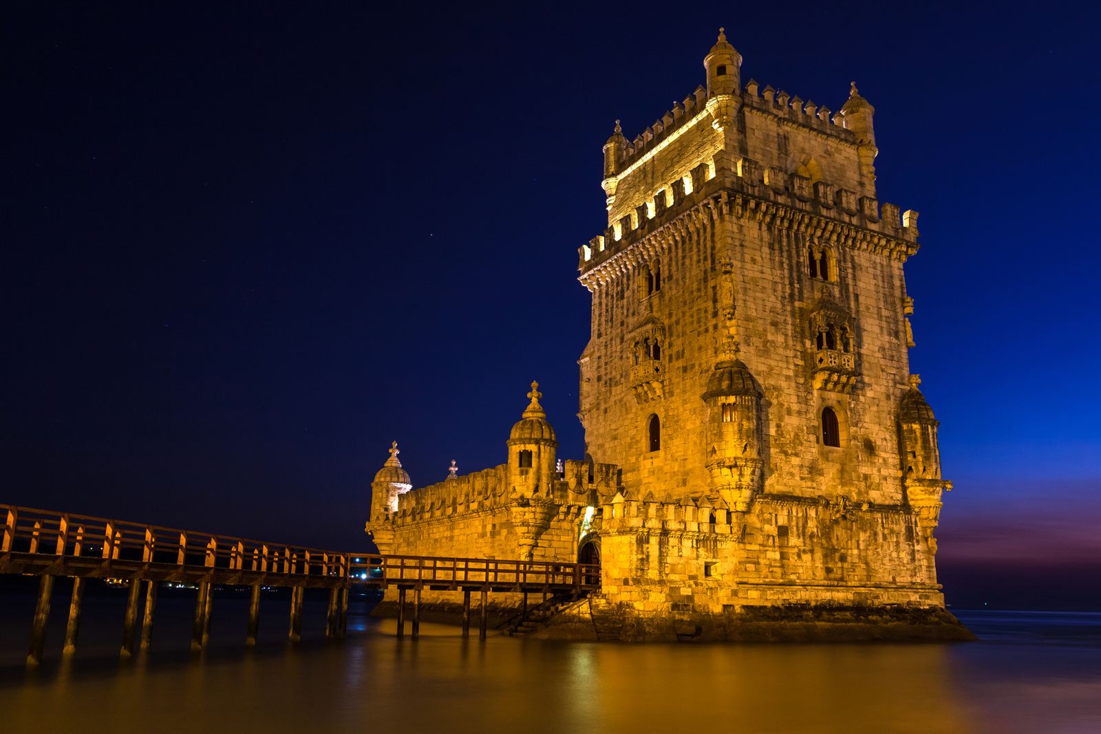 Belem Tower in Lisbon floodlit at night on the Tagus River shore