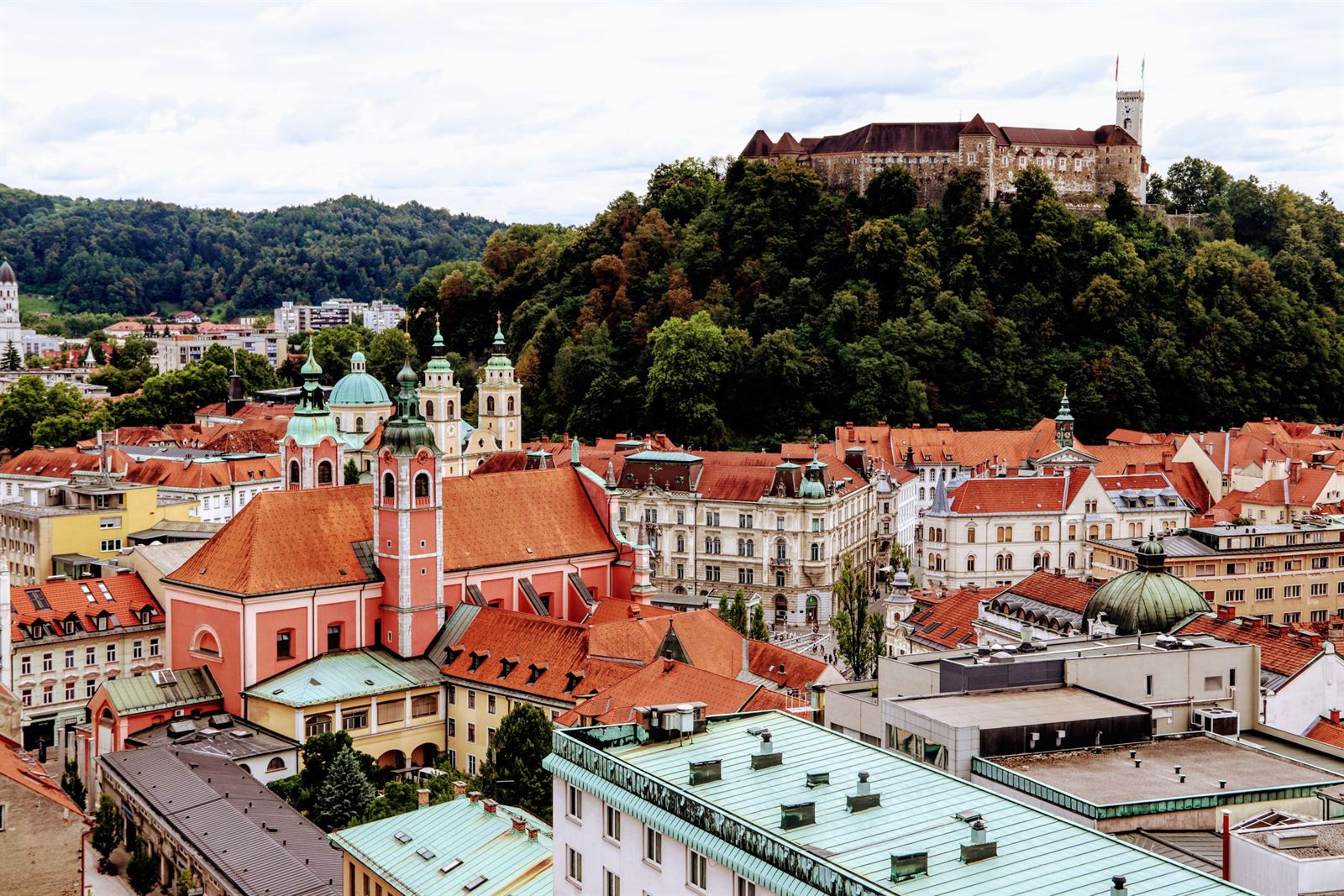 Ljubljana old town red roofs and pink Franciscan Church below the hilltop Ljubljana Castle