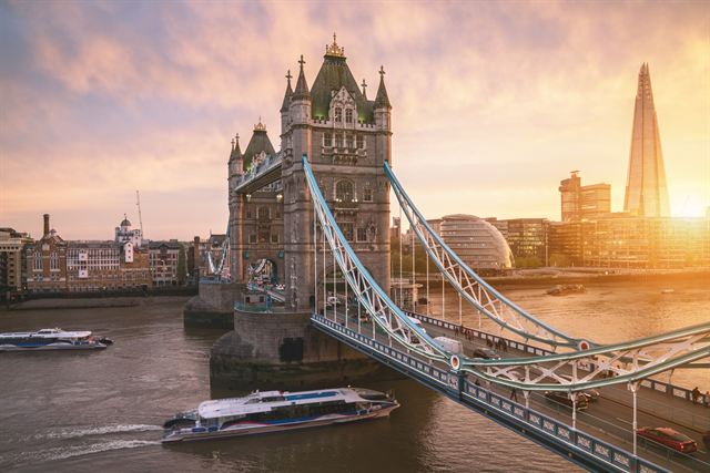 Tower Bridge at sunrise with a boat on the Thames and the Shard in the background