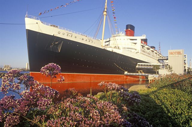 The Queen Mary ocean liner docked in Long Beach behind a bed of flowers