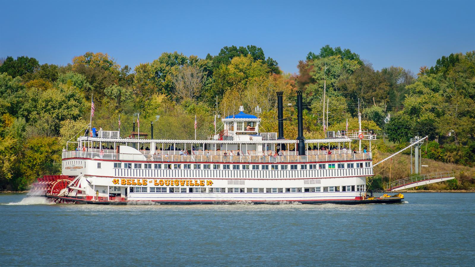Belle of Louisville sternwheeler steaming along the Ohio River past autumn trees
