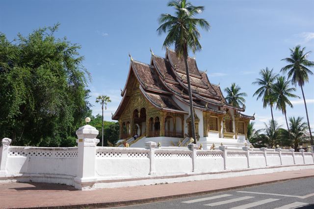 Haw Pha Bang temple at the Royal Palace compound in Luang Prabang, tiered golden roofs behind white wall