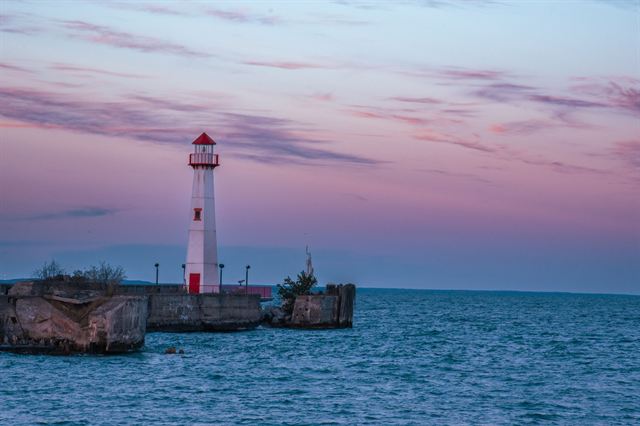Red and white lighthouse on a breakwater off Mackinac Island at a pastel sunset
