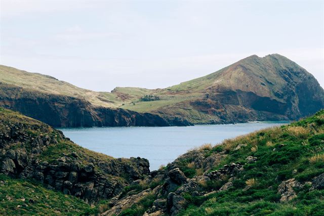 Green hills and a sheltered sea bay on the rugged coast of Madeira island