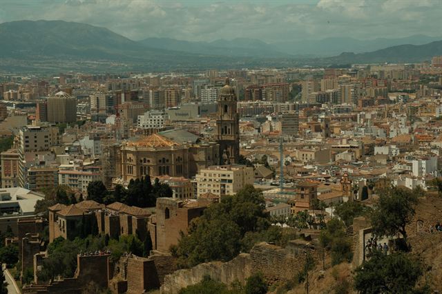 Málaga Cathedral tower and old town rooftops seen from the Alcazaba hill with mountains behind