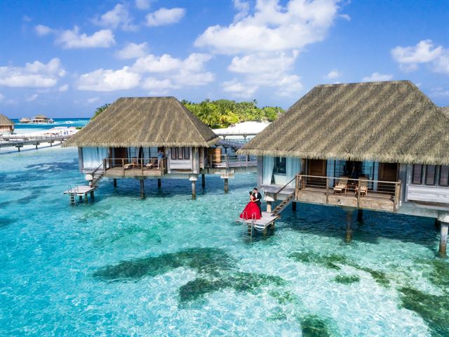 Thatched overwater villas above clear turquoise lagoon water in the Maldives