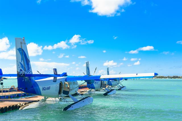 Seaplanes with Maldivian 8Q registration moored at a floating dock in a turquoise lagoon