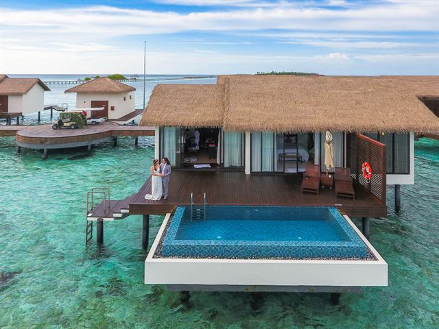 Aerial view of an overwater villa with private plunge pool over a Maldives reef