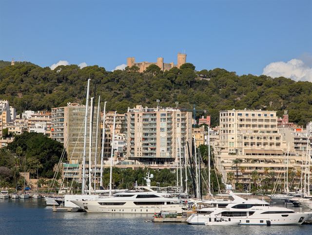 Palma de Mallorca marina with luxury yachts, waterfront hotels and hilltop Bellver Castle