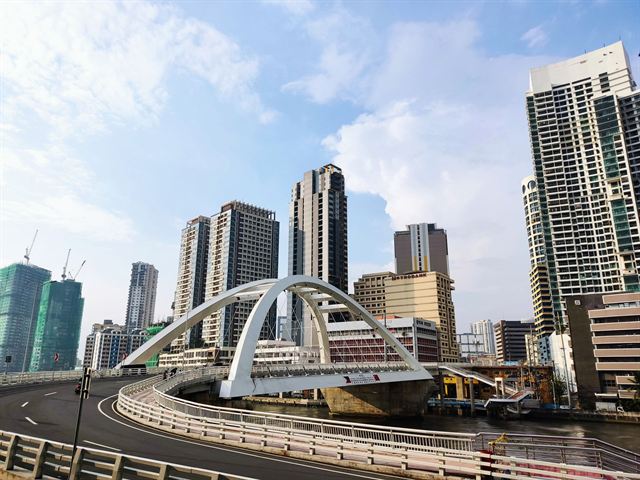 Binondo-Intramuros Bridge's white arch over the Pasig River with Manila high-rises behind