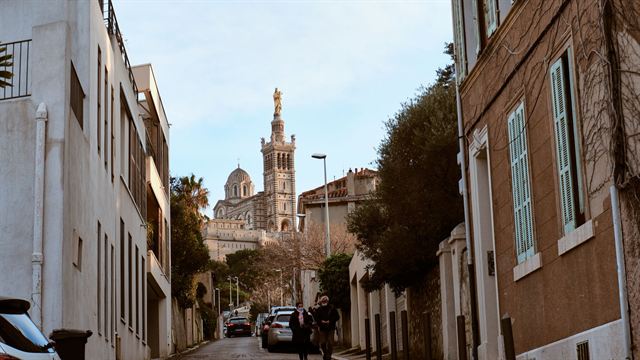 Basilica of Notre-Dame de la Garde on its hill seen at the end of a Marseille street