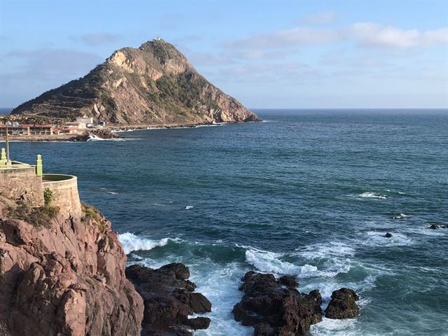 Rocky Pacific shore with crashing waves and a steep headland hill on the Mazatlan coast