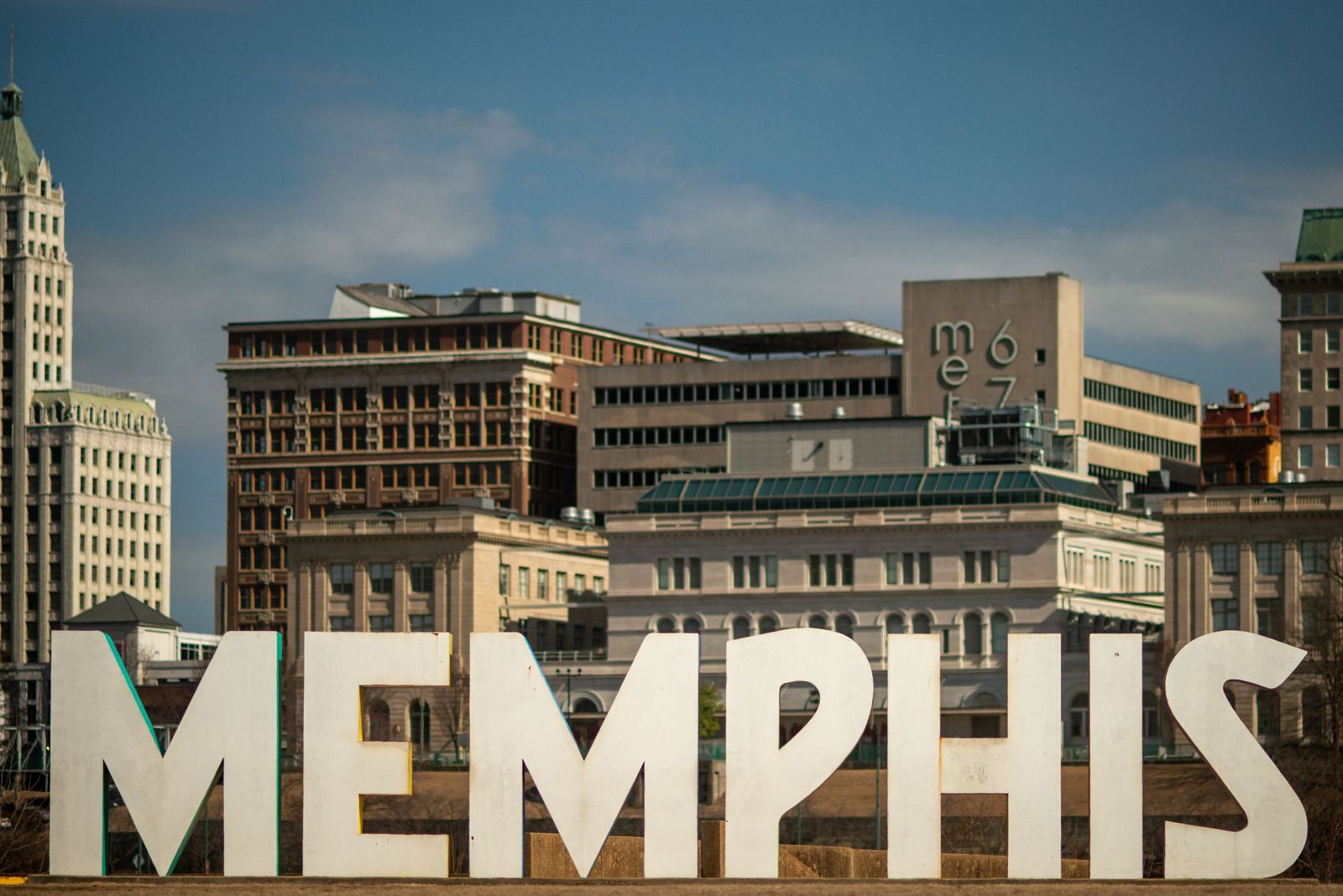 Giant white MEMPHIS letters sculpture in front of historic downtown Memphis buildings and towers