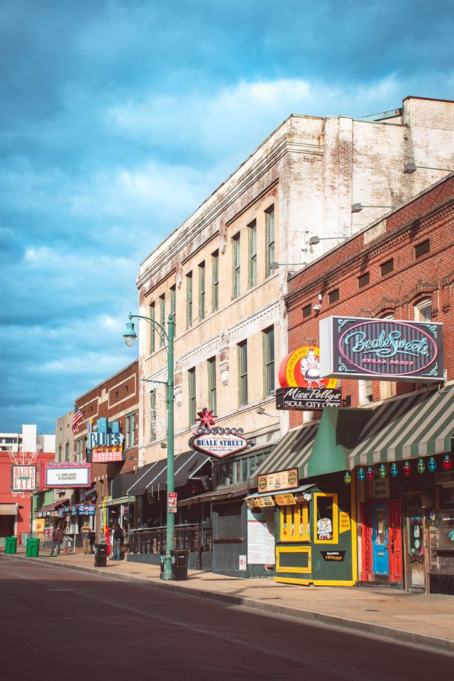 Historic brick storefronts and neon signs lining Beale Street in downtown Memphis on a sunny day