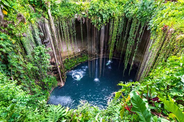 Ik Kil cenote near Chichen Itza with hanging roots above deep blue water