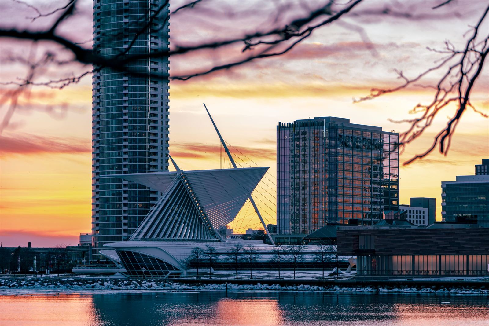 Milwaukee Art Museum's winged Calatrava pavilion and lakefront towers silhouetted against an orange sunset