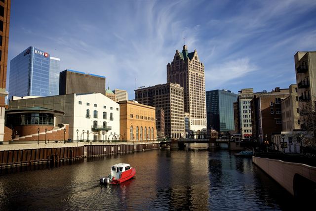 Milwaukee River winding through downtown with a red tour boat and historic and modern buildings
