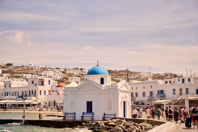 Small blue-domed Agios Nikolaos chapel on the Mykonos Town harborfront with whitewashed buildings