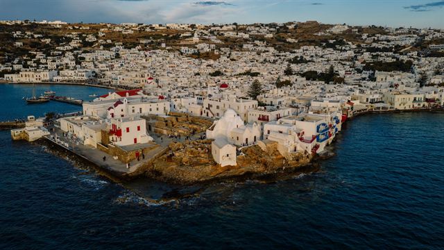 Aerial view of Mykonos Town's whitewashed houses spread along the coast and harbor