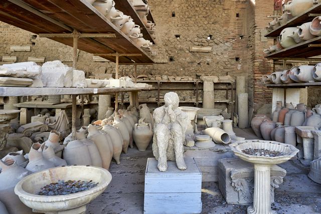 Plaster cast of a Pompeii victim among amphorae in a storeroom at the ruins
