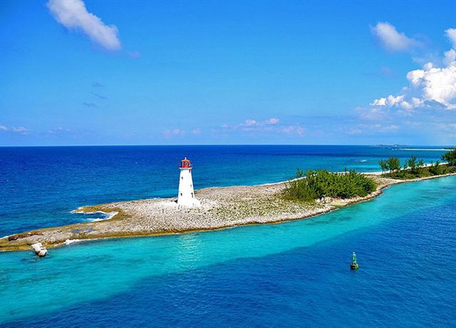 Aerial of the white Paradise Island lighthouse on a rocky point at Nassau harbour entrance, turquoise water