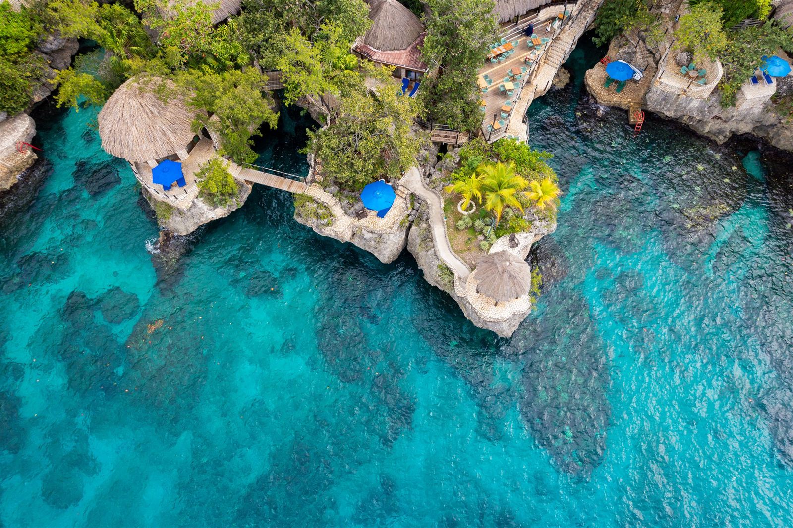 Aerial view of the Negril West End cliffs with thatched cottages and turquoise sea at Rockhouse