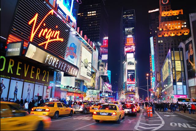Times Square at night with neon billboards and yellow taxis