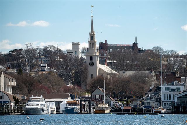 Newport Harbor waterfront with moored yachts and the white steeple of Trinity Church above the town