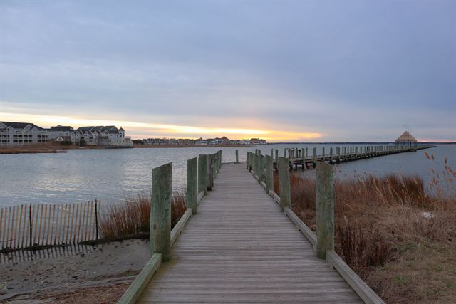 Wooden dock over the bay in Ocean City, Maryland with waterfront homes at dusk