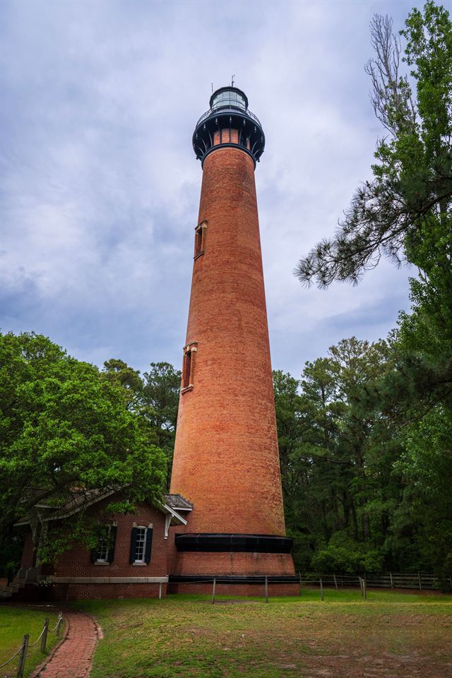 Red-brick Currituck Beach Lighthouse rising above trees in Corolla on the Outer Banks