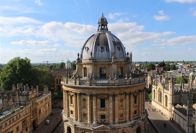 Radcliffe Camera's domed rotunda among Oxford college buildings seen from above on a sunny day