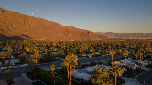 Aerial view of palm-lined Palm Springs neighborhoods beneath the San Jacinto Mountains at sunset