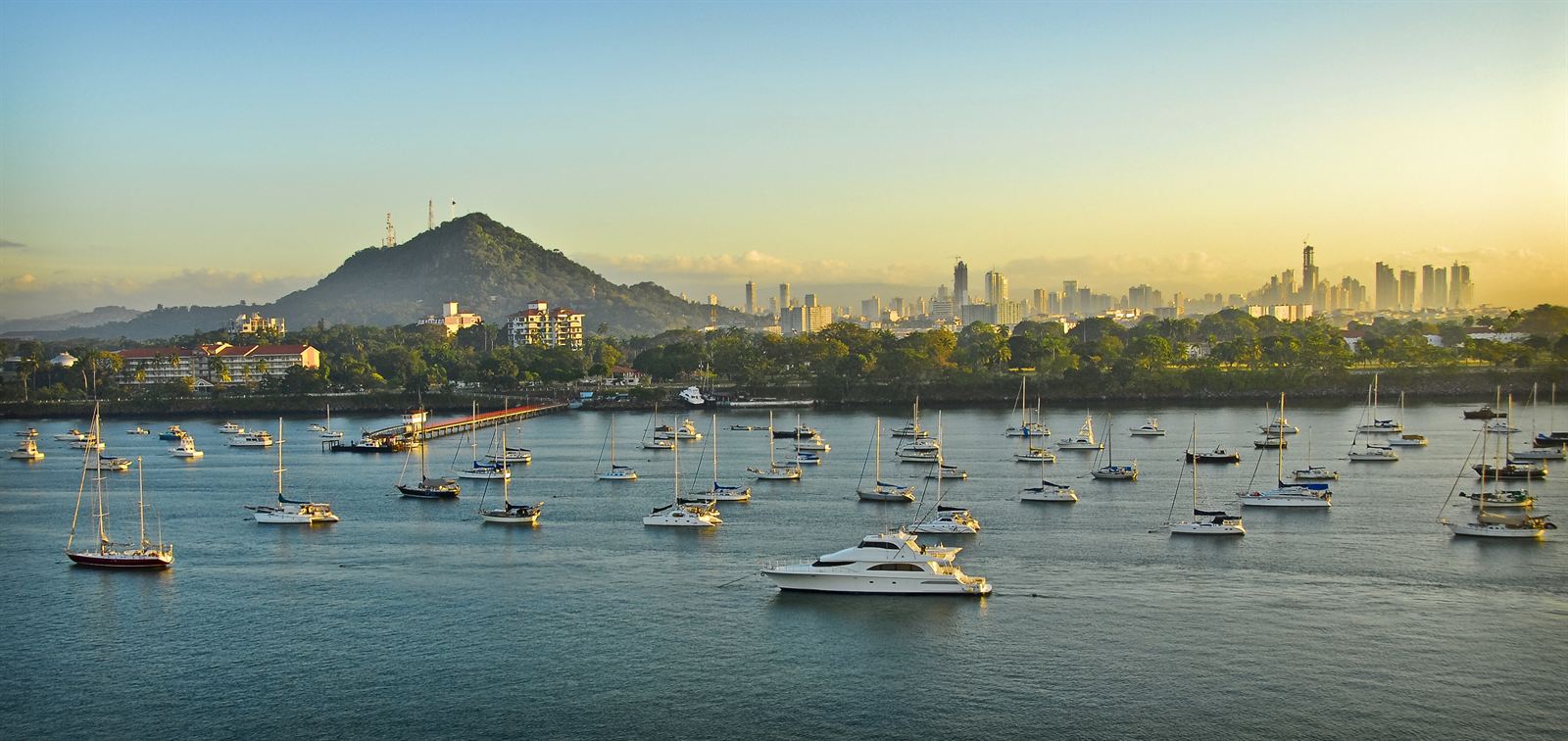 Panama City skyline and Cerro Ancon behind a bay full of moored sailboats at sunrise