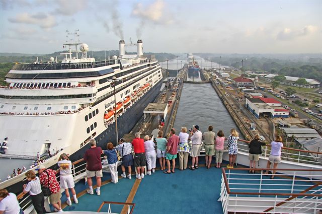 Passengers on a cruise ship bow watching a Panama Canal lock ahead, cruise ship alongside