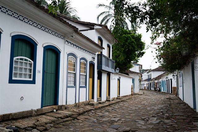 Cobblestone street with whitewashed colonial houses, green doors and blue window frames in Paraty