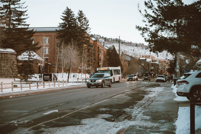 Snowy winter street in Park City, Utah with brick lodges, pine trees and a shuttle bus