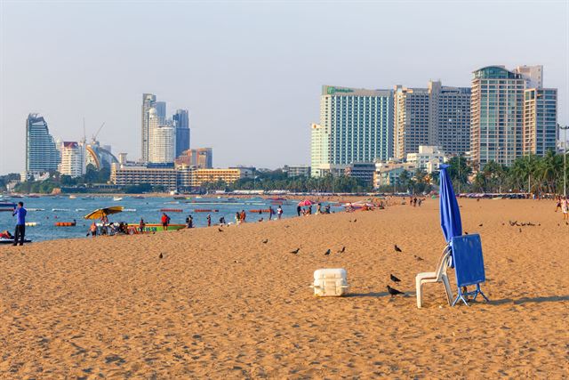 Pattaya Beach's golden sand with umbrellas and the city's high-rise hotel skyline behind