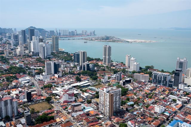 Aerial view of George Town, Penang's red roofs and high-rises along the coast and reclaimed land