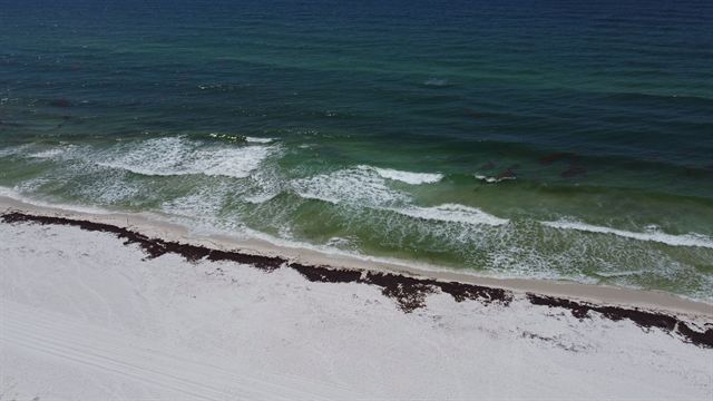 Aerial view of turquoise Gulf waves breaking on the sugar-white sand of Pensacola Beach, Florida